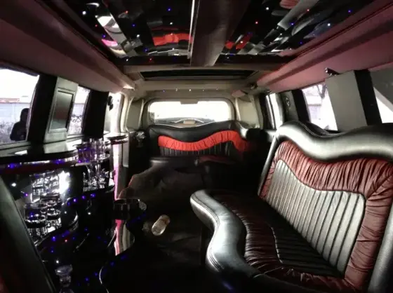 Interior de limusina Hummer rosa con asientos rojos y negros