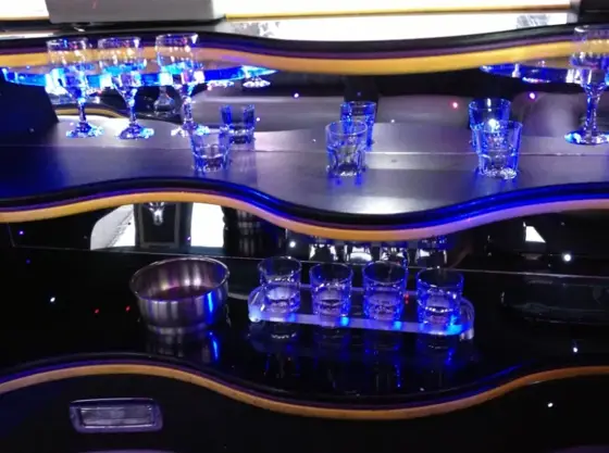 Interior de limusina Hummer blanca con barra iluminada en azul
