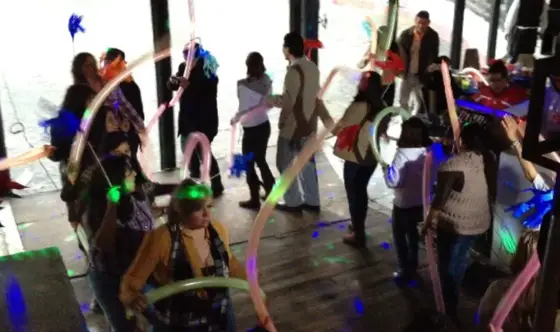 Invitados bailando con globos largos y luces en una batucada
