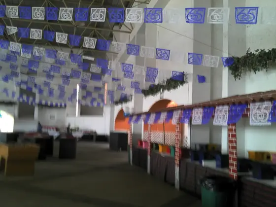 Interior del lienzo con papel picado y mesas montadas para banquete