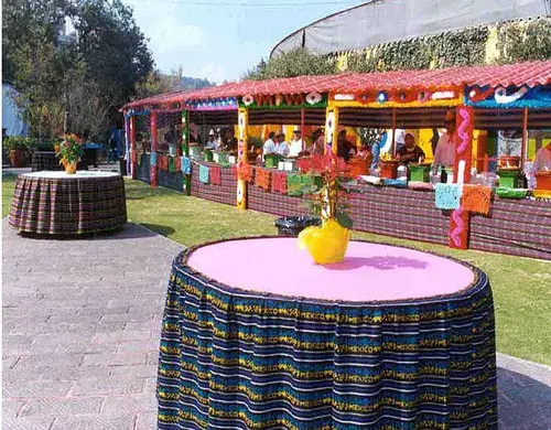 Mesa con mantel multicolor y puestos de comida mexicana en jardín al aire libre