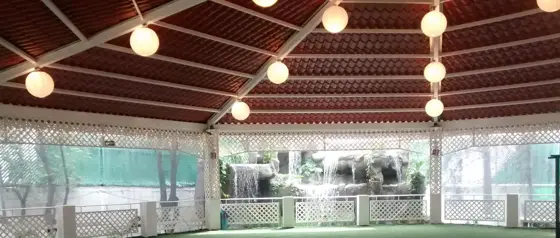 Terraza techada con luces y cascada de piedra al fondo