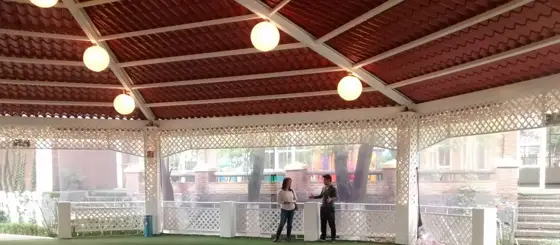 Terraza techada con luces redondas, celosía blanca y jardín
