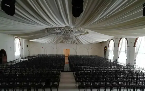 Capilla con cortinaje blanco, candil y sillas negras