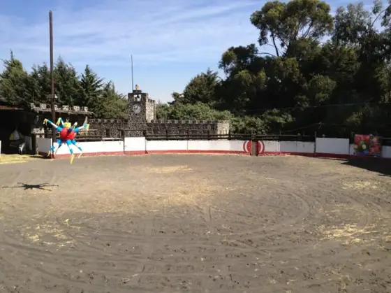 Ruedo de arena con piñata colgante y muros de piedra