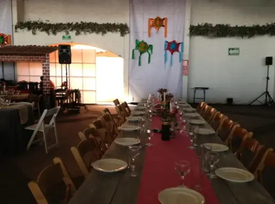 Mesa larga de banquete con mantel rosa y sillas de madera