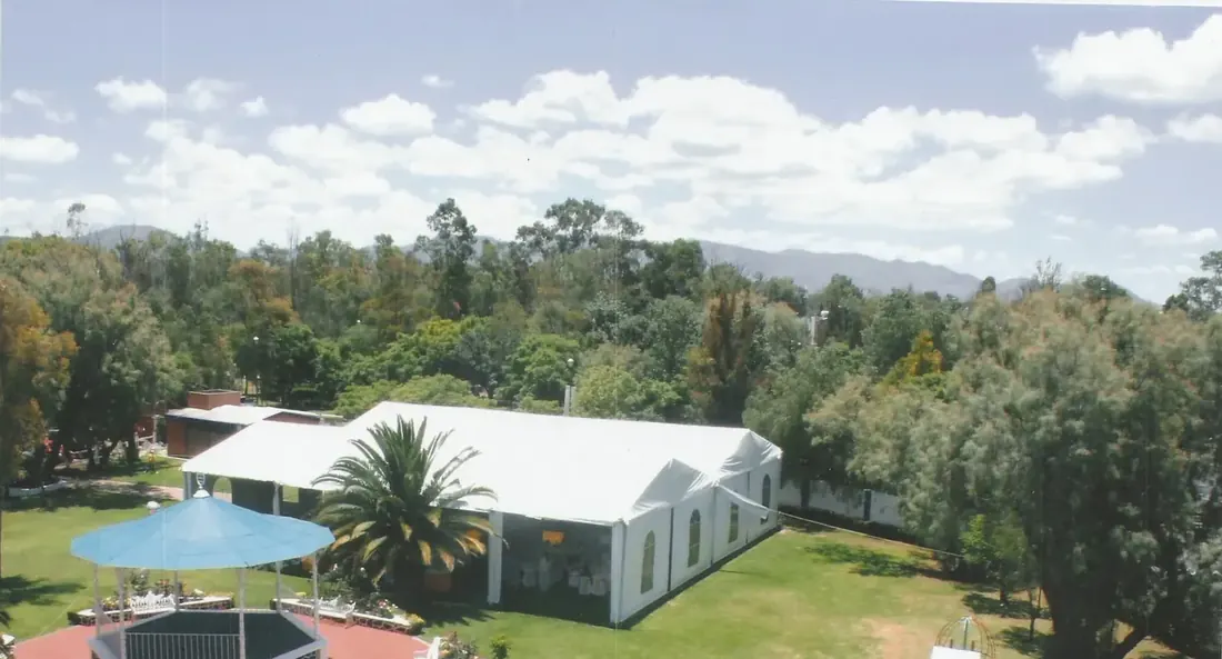 Vista aérea del jardín con kiosco, carpa blanca y área de juegos