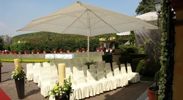 Sillas con fundas blancas y arreglos florales en una terraza del Lienzo Charro del Pedregal