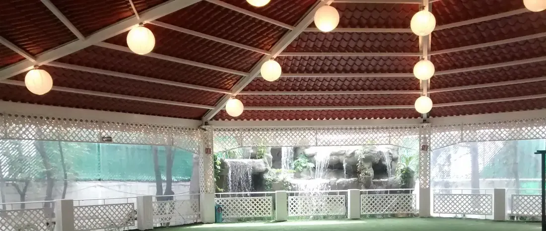 Terraza techada con luces y cascada de piedra al fondo