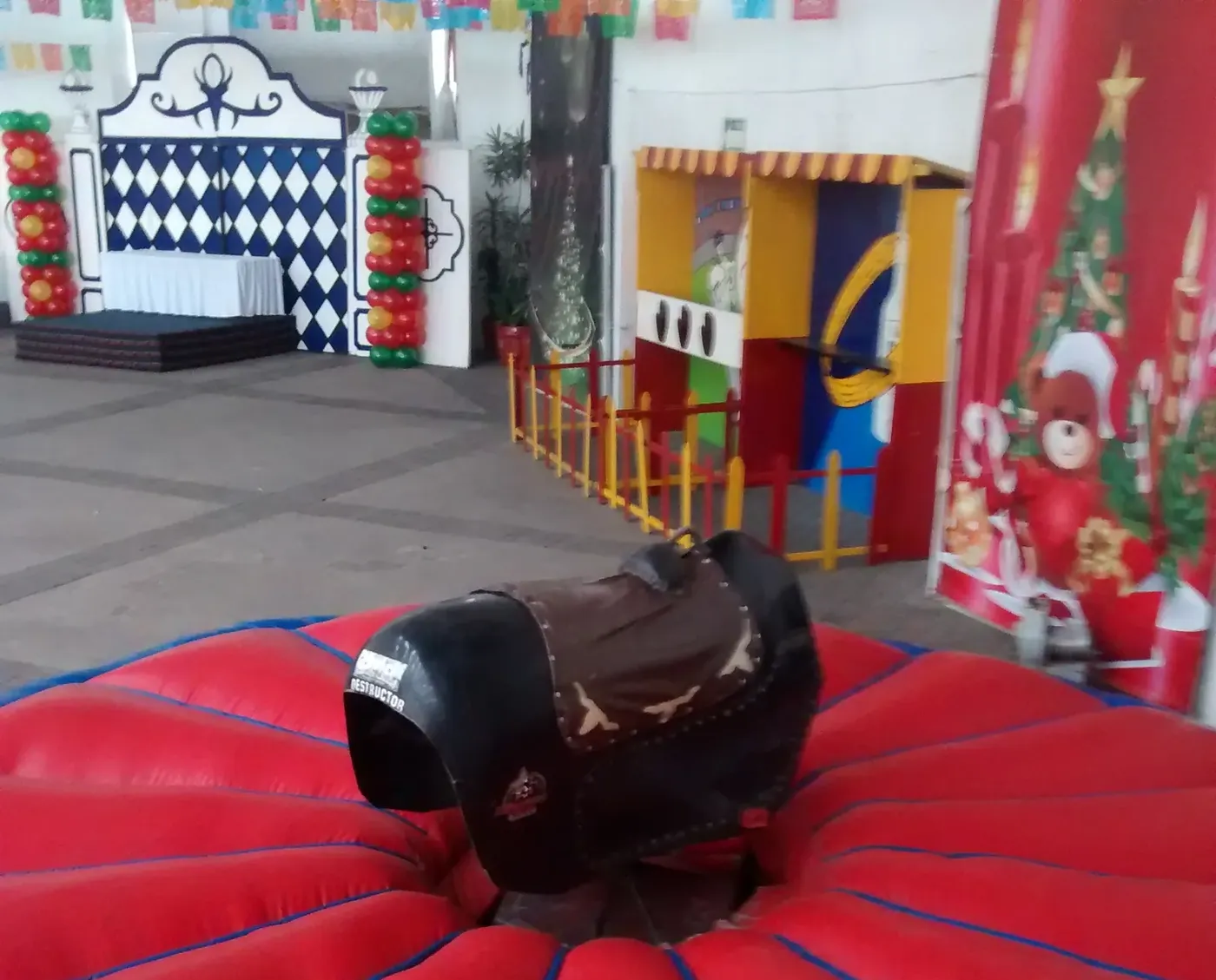 Toro mecanico negro sobre colchon inflable rojo en salon de fiestas