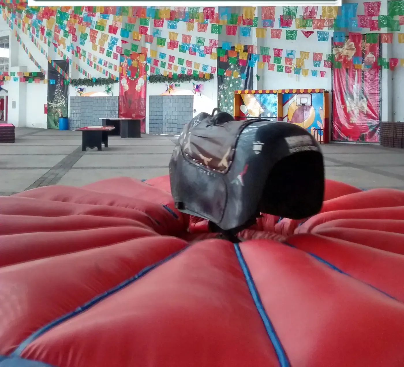 Toro mecanico con colchon inflable rojo en un salon decorado con papel picado