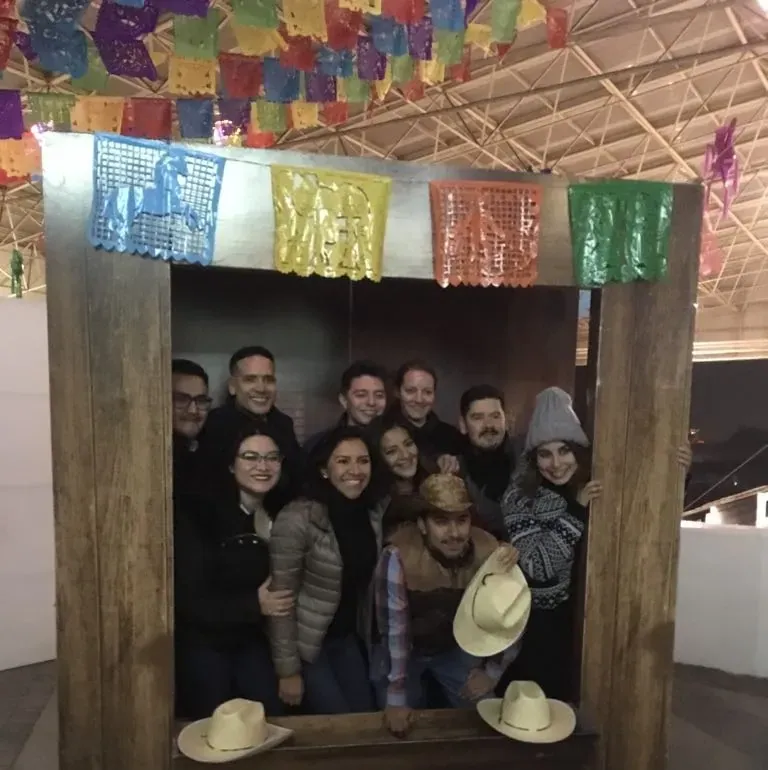 Invitados posando en un marco rústico de fotos con sombreros charros