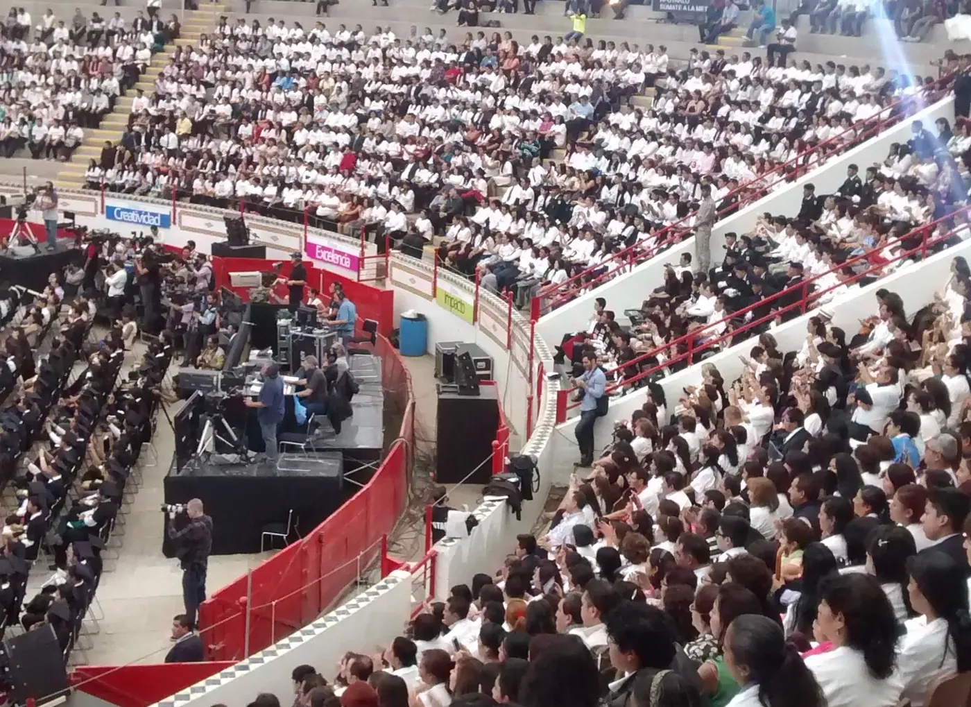 Gradas llenas de asistentes durante un evento masivo en recinto techado