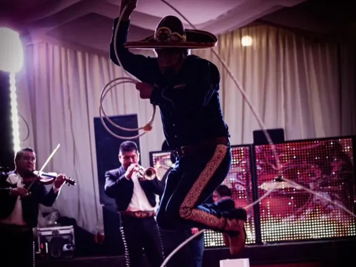 Charro haciendo floreo de reata con mariachi en un evento de XV años